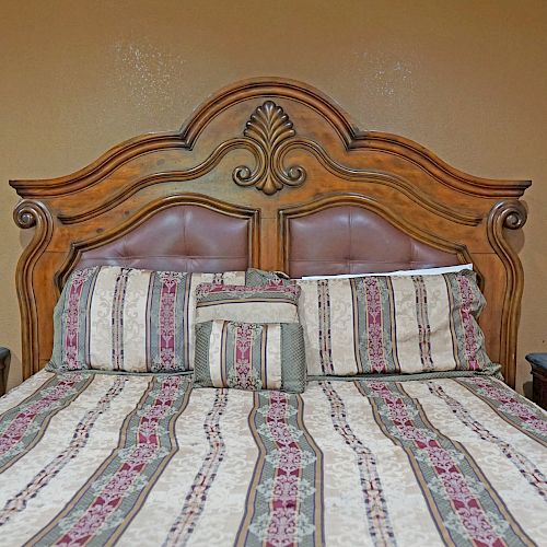 A bed with a wooden headboard, patterned bedspread, and matching pillows, accompanied by two nightstands with drawers on either side, is shown.