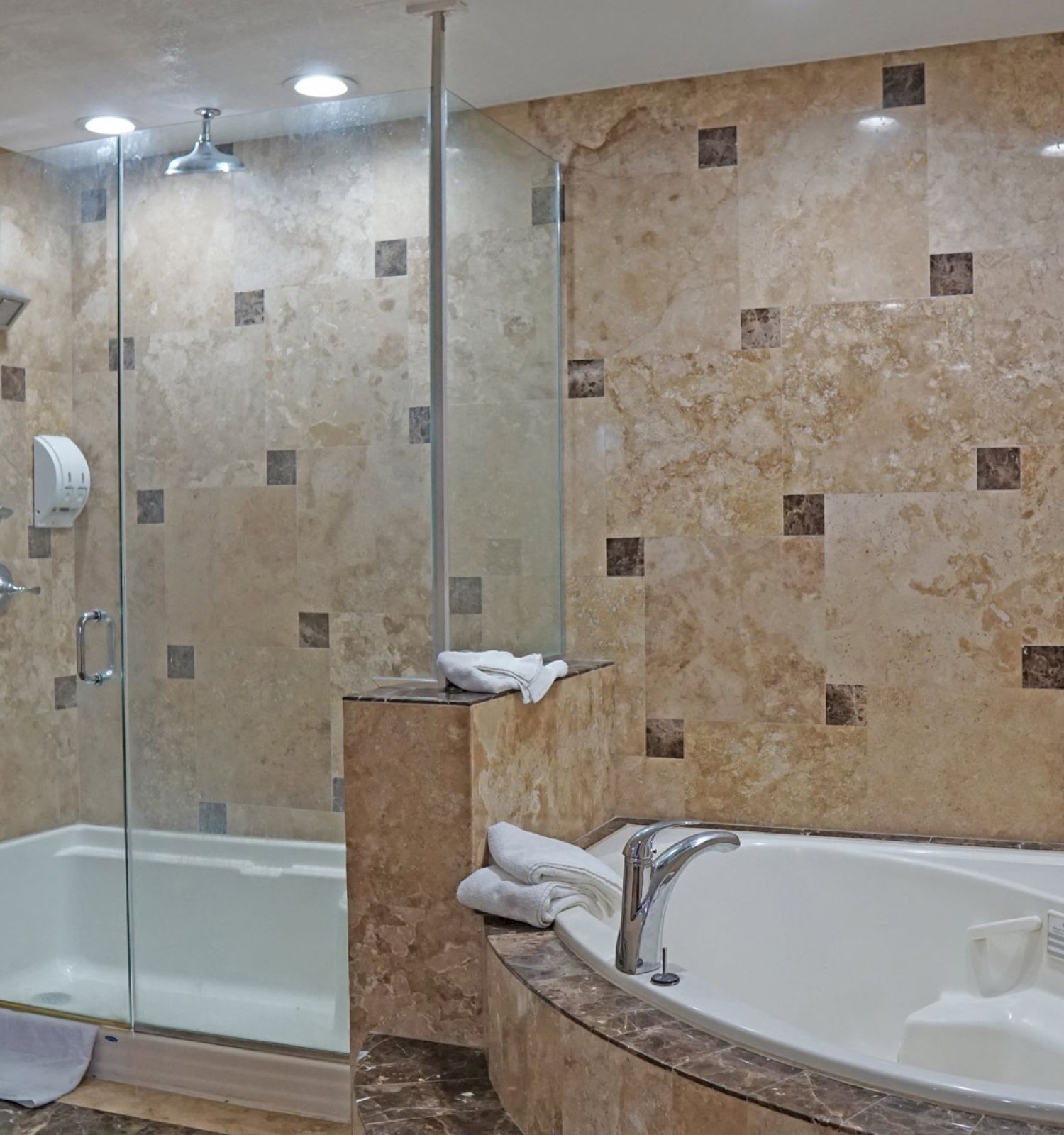 This image shows a luxurious bathroom with a glass-enclosed shower and a large bathtub, both featuring marble or tile surroundings.